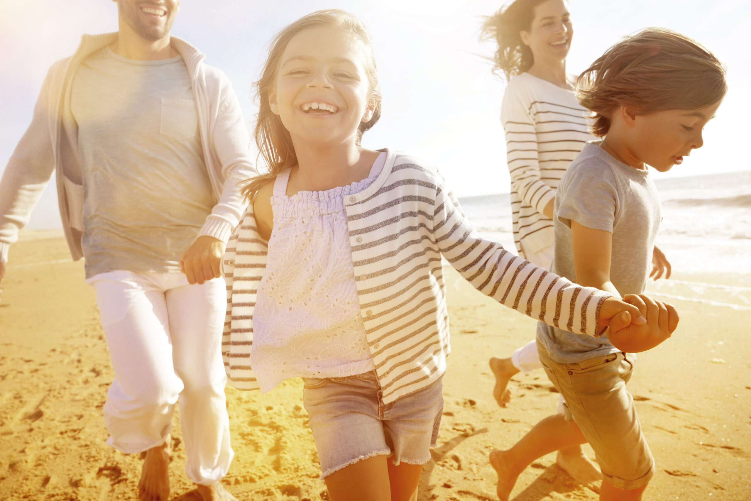 Family running on sandy beach at sunset